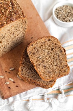 Taze çavdar ekmeği dilimleri. Tahta kesme tahtasındaki tohumlarla yakın mesafede..