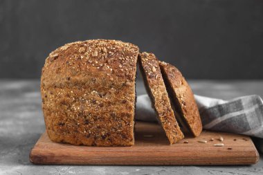 Tahtada taze dilimlenmiş çavdar ekmeği. Sağlıklı ekmek ve gri bir zemin..