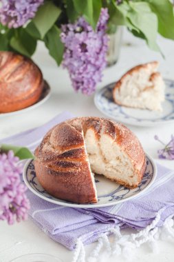 Masada üzerinde leylak çiçekleri olan taze dilimlenmiş tarçınlı çörek. Kanelbullar - İsveç tarçını ruloları.