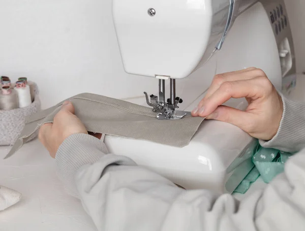 Woman hands with dress at modern sewing machine. Workplace with sewing machine.