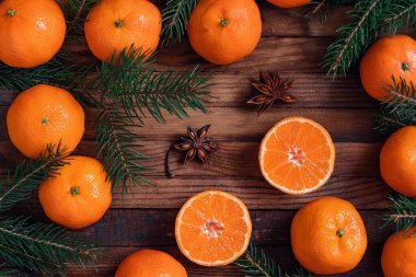 Olgunlaşmış taze mandalinalar, yıldız anasonu ve koyu ahşap bir tahtanın üzerindeki köknar dallarıyla Noel kompozisyonu. Üst Manzara. Boşluğu kopyala.