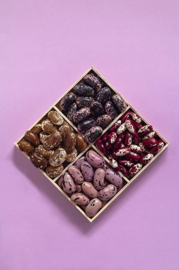 Mavi arka planda tahta bir kutuda organik fasulye seti. Kırmızı koşucu, Anasazi fasulyesi. Üst Manzara. Boşluğu kopyala.