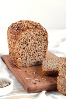 Tahtada taze dilimlenmiş çavdar ekmeği. Ayçiçeği tohumlu sağlıklı ekmek ve beyaz arka planda keten..
