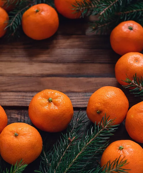 Fresh organic orange tangerines and fir tree branches on a wooden board. Copy space.