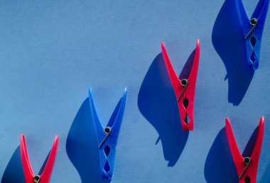 Sert ışıkta mavi arka planda parlak pembe ve mavi plastik mandallar. Boşluğu kopyala.