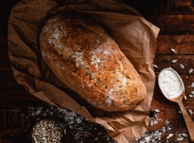 Taze pişmiş çavdar ekmeği, ahşap bir masada ayçiçeği tohumları. Üst görünüm.