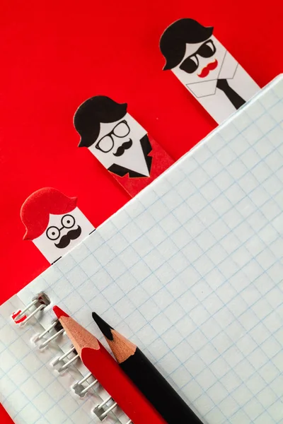 Open notebook, stickers, red and black pencils on a red background. Copy space. Office and education concept.