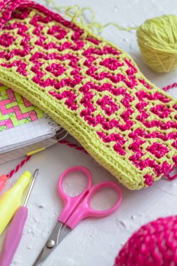 Geometrik etnik model. Rhombus - parlak pembe tuval. Tığ işi kumaş, tığ işi kanca, defter, makas..