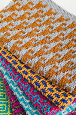 Geometrik desenli parlak renkli örgü kumaş yığını. Renkli örülmüş doku. Sanat el yapımı konsept.