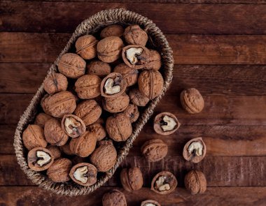 Koyu ahşap bir arka planda oval hasır sepetteki cevizler. Boşluğu kopyala.