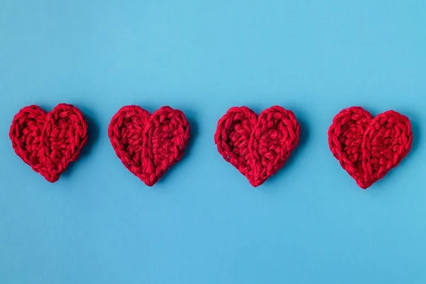 青い背景に4つの赤いかぎ針編みの心 ハッピーバレンタインの日のコンセプト 最上階だ スペースのコピー ストックフォト