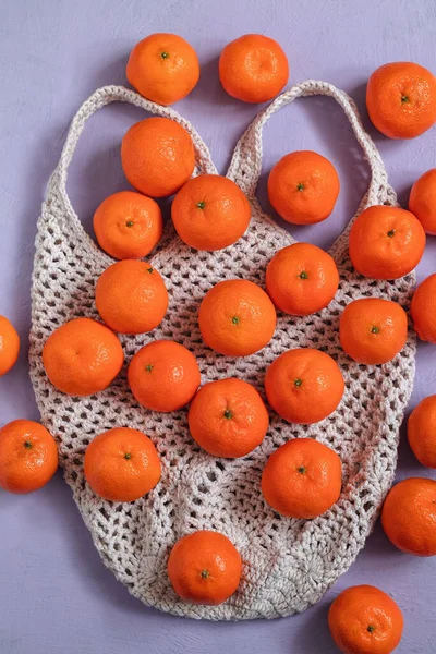 Fresh organic tangerines or clementines on cotton mesh crochet bag. Eco friendly shopping and zero waste concept.