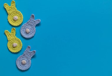 Easter composition. Funny yellow and blue bunnies with white tails on a blue background. Top view. Copy space.