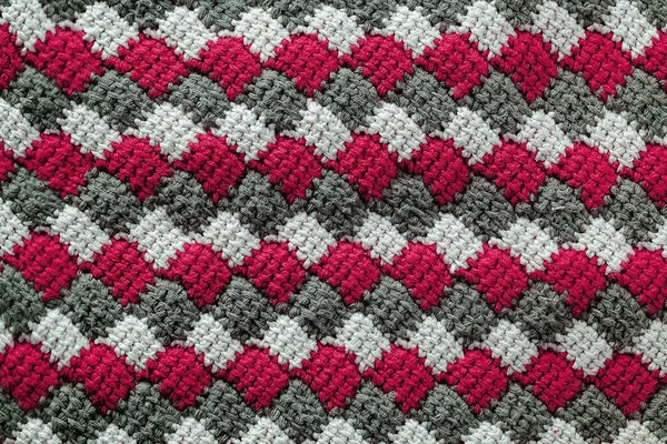 Tunisian crochet fabric. Fuchsia white grey knitted background. Crochet tunisain entrelac.
