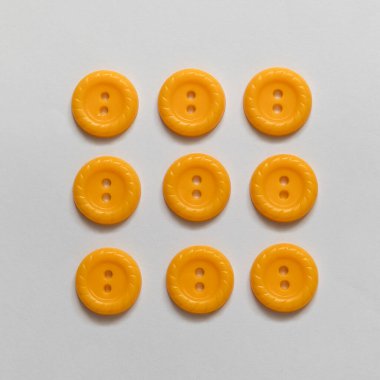 Beyaz arka planda sarı plastik düğmeler. Dikiş aletleri. Üst görünüm.