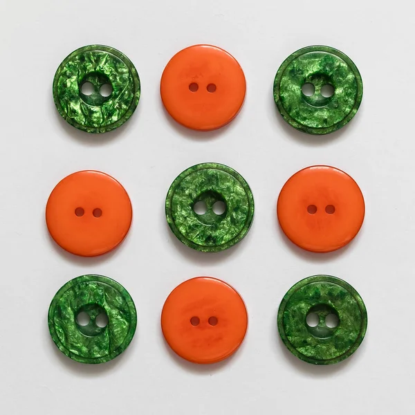 stock image Set of green and orange plastic buttons on a white background. Sewing tools. Top view.