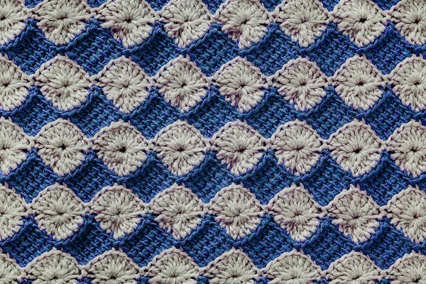 White and blue crochet floral pattern. Crochet tunisian pattern. Knitted texture.
