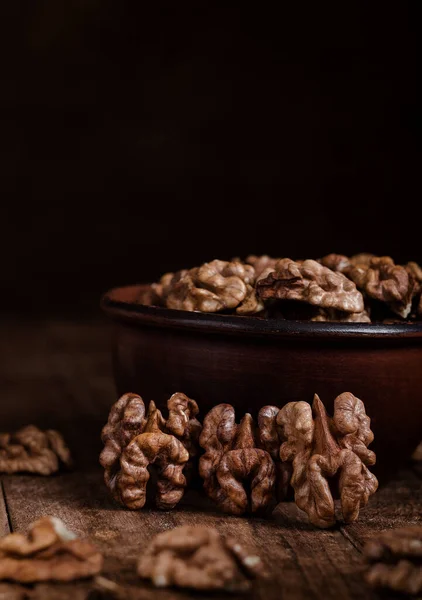 Stock image Organic dried walnut kernels next to the ceramic bowl on a dark wooden table. Walnut kernels close up. Brain food