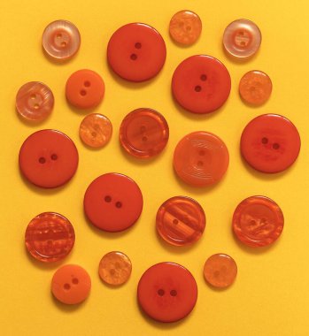 Sarı arka planda farklı boyutlarda bir sürü turuncu düğme var. Üst görünüm.