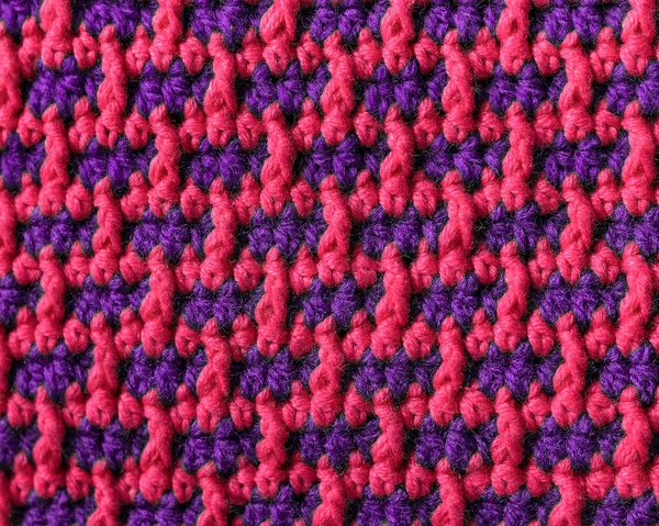 Seamless crochet pink purple fabric with brick pattern. Knitted background.