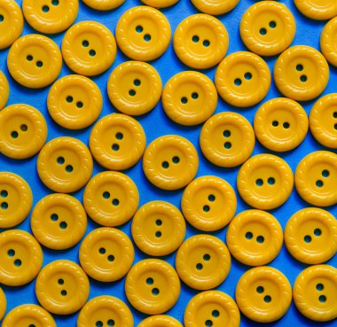 Sarı dikişli plastik düğmeler mavi arkaplanı kapatır. Dikiş arkaplanı.