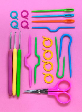 Pembe arka planda parlak renkli örgü ve örgü aletleri. Düz yatıyordu.