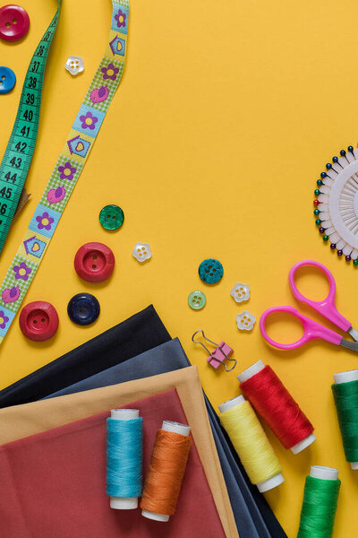 Bright colorful sewing tools on a yellow background.