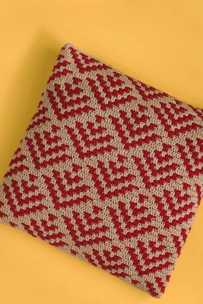 黄色の背景に現代的な柔らかいかぎ針編みの枕 抽象的なモザイクパターンの赤いベージュのかぎ針編みの枕 — ストック写真