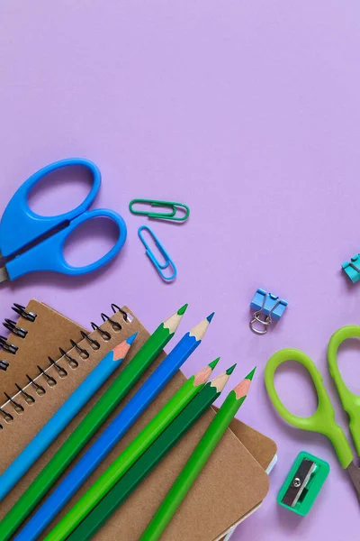 School stationery and two notebooks on a purple background. Top view. Copy space.