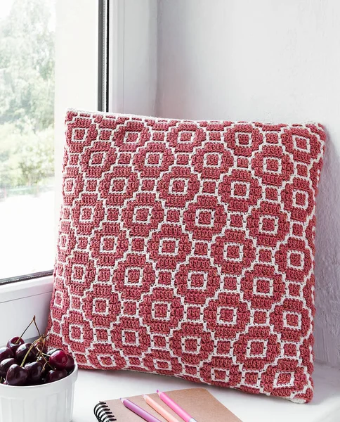 窓辺の赤いかぎ針編みの枕 抽象的なモザイクパターンの手作りのかぎ針枕 — ストック写真