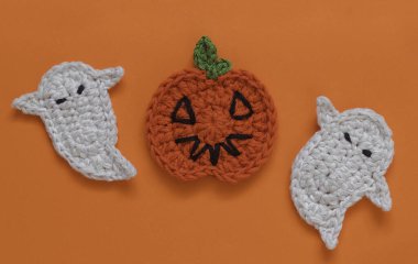 Turuncu arka planda örgü ören Cadılar Bayramı balkabakları ve hayalet. El yapımı Cadılar Bayramı dekoru. Uzayı kopyala Üst görünüm.