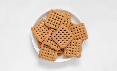 Beyaz arka planda tatlı kare bisküviler ile beyaz tabak.