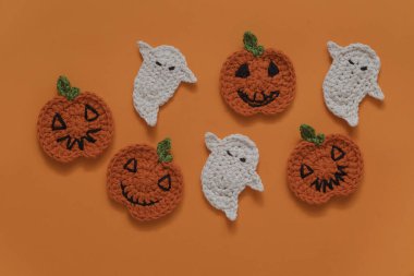 Turuncu arka planda Cadılar Bayramı tığ işi dekoru. El yapımı portakal kabakları ve beyaz hayalet..