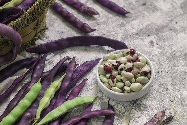 Masada taze organik fasulye ve mor fasulye kabukları olan bir kase..