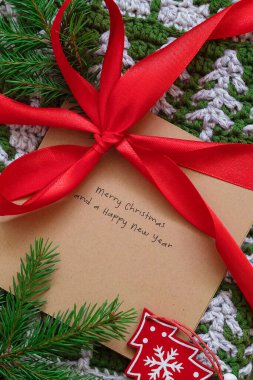 Noel tebrik kartı, kırmızı kurdeleli tığ işi hediye. Noel konsepti.