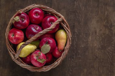 Ahşap bir arka planda hasır sepetteki organik kırmızı elmalar. Üst Manzara. Boşluğu kopyala.