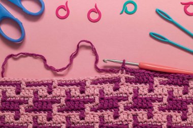 Soyut mozaik desenli mor örgü kumaş. Pembe arka plana yakın. Üst Manzara. Boşluğu kopyala.