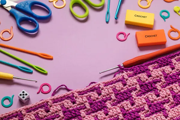 Knitted background with bright crochet fabric and crochet tools. Copy space.