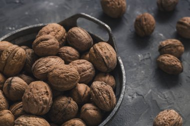 Gri arka planda, organik cevizler ve dökme demir bir kase..