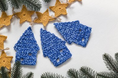 El yapımı tatiller. Tığ işi mavi Noel evleri ve beyaz arka planda sarı yıldız çelenkleri. Üst Manzara. Boşluğu kopyala.