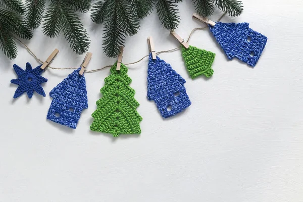 Handmade crochet garland made of Christmas tree gingerbread house and snowflake on a white background. Top view. Copy space.