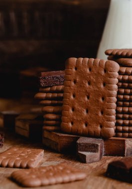 Kırsal ahşap arka planda sütlü siyah çikolatalı kurabiyeler. Çikolatalı krakerler kapanıyor..