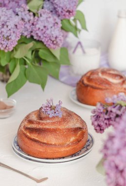 Süt şişesi ve leylak çiçekli taze tarçınlı çörekler. Kanelbullar - İsveç tarçını ruloları.
