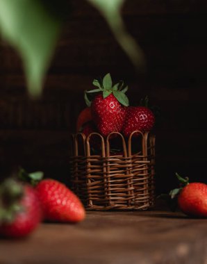 Siyah ahşap bir masada kırmızı çilekli sepet. Organik mevsimlik meyveler..