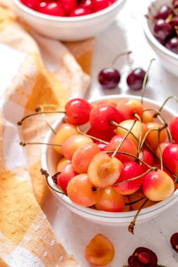 Taze yaz sarısı kirazı beyaz bir kasede kapanıyor. Organik böğürtlenli sağlıklı kahvaltı..