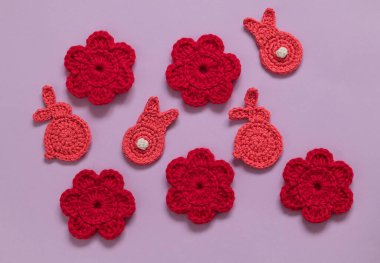 Örgü ören Paskalya çiçekleri ve mor arka planda tavşanlar..