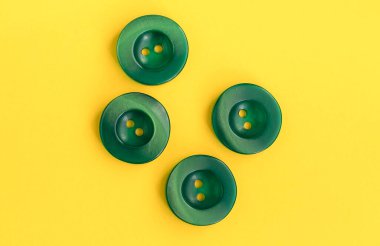Turquoise plastic buttons on a yellow background. Sewing tools. Top view. Copy space.