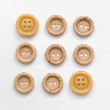 Beyaz arka planda bej renkli plastik düğmeler. Dikiş aletleri. Üst görünüm.