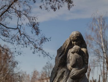 5 Nisan 2022. Novograd-Volynskyi, Zhytomyr bölgesi, Ukrayna. Mavi gökyüzü arka planında çocuk heykeli olan anne.