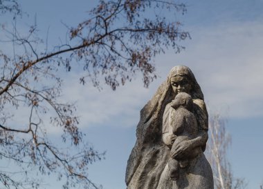 Mavi gökyüzü arka planında, kollarında taş heykeli olan bir anne. Novograd - Volynsky, Zhytomyr bölgesi, Ukrayna.
